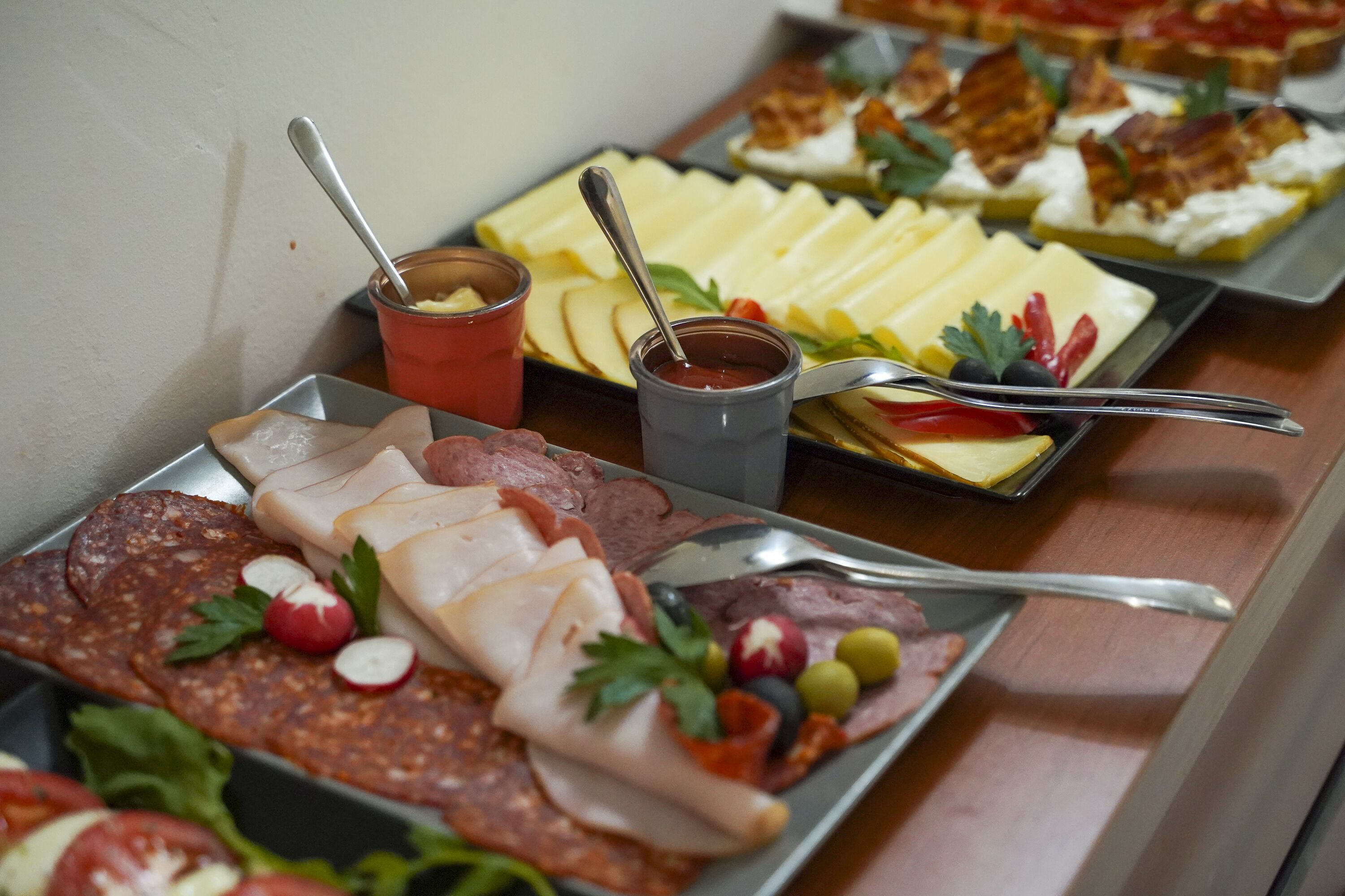 Une variété d'aliments, notamment des viandes tranchées, des fromages et des accompagnements, présentés sur des plateaux.