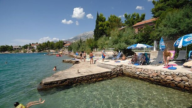 A beach with clear water, people swimming and sunbathing, and umbrellas. - Villa Vicko (Starigrad)