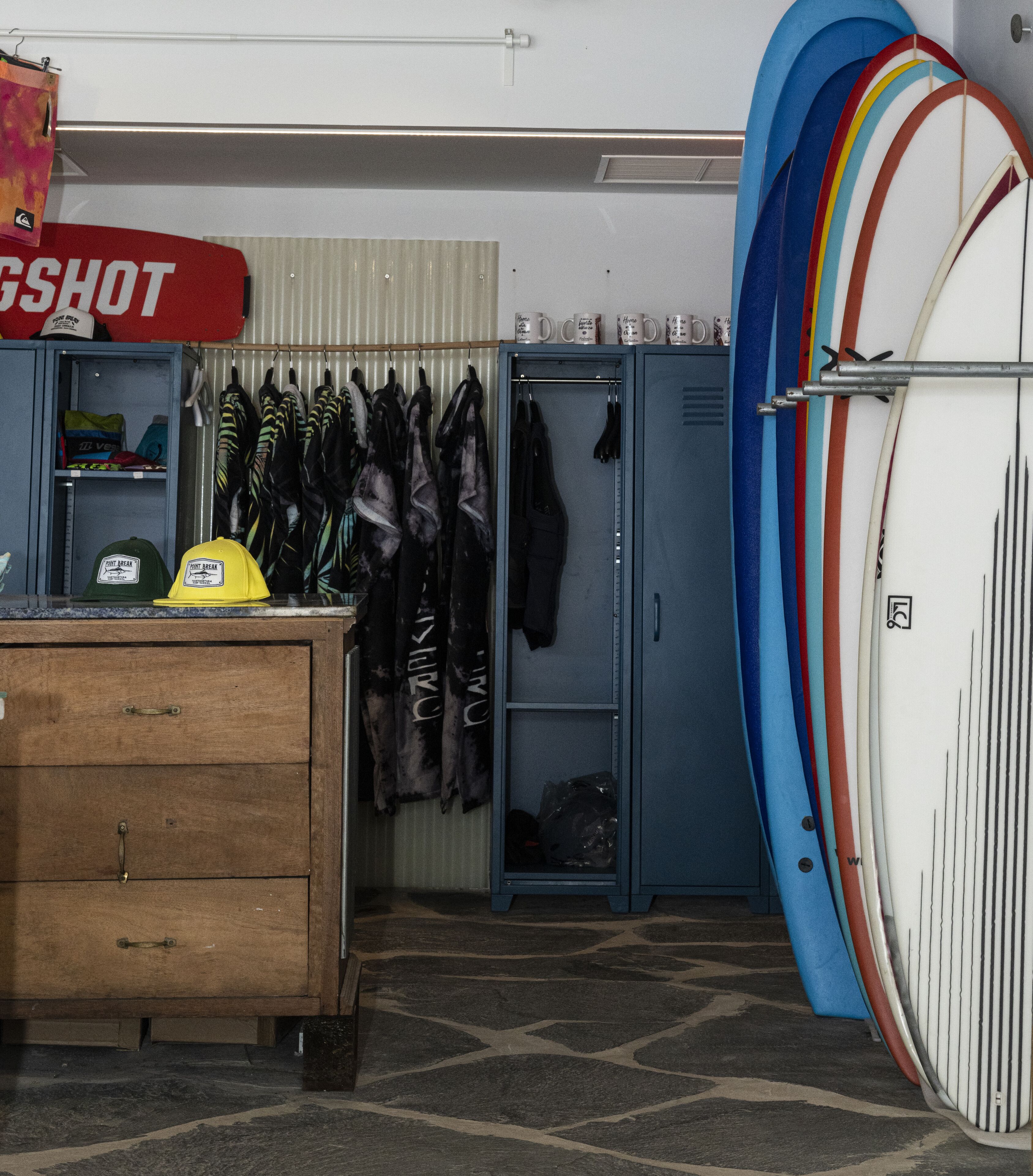 A room with a surfboard rack, a wooden dresser, and a sign that reads "GSHOT".