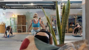 A yoga class in a studio with mirrored walls, wooden furniture, and a mural.