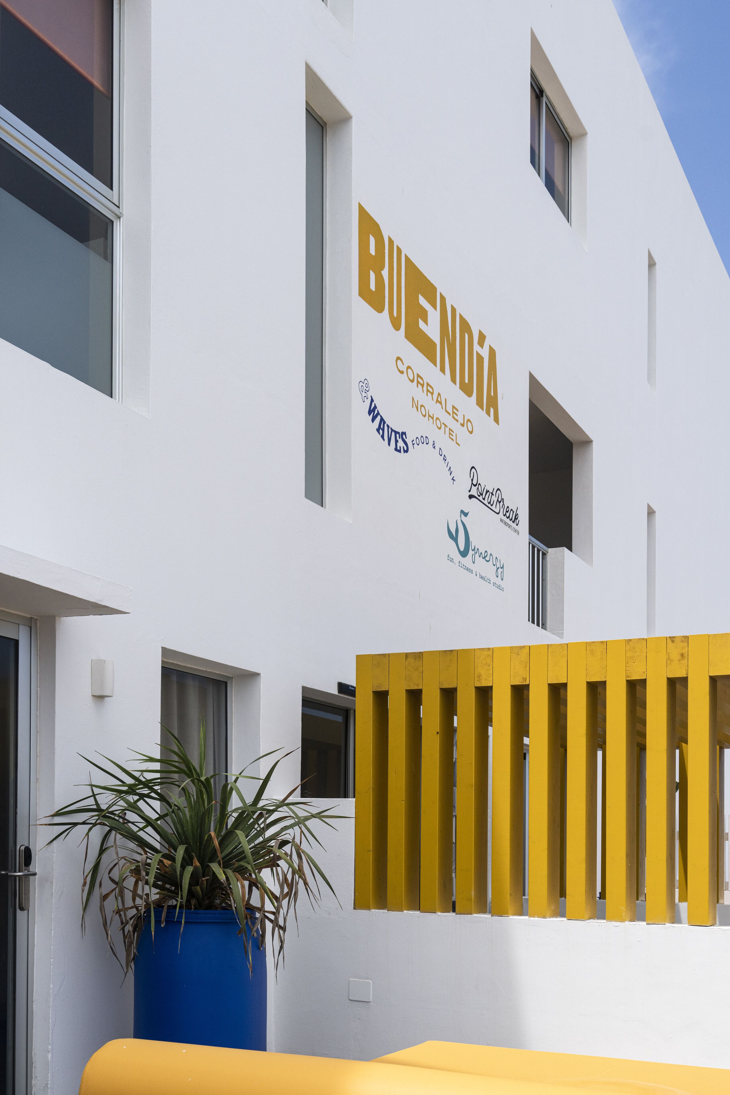 A building with a sign reading "BUENDIA CORRALHO NOHOTEL" and logos for "PaintBrush" and "Synergy".