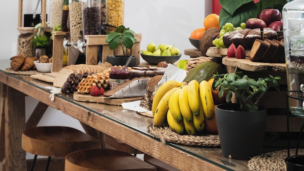 Une table à manger en bois, surmontée d’un plateau en verre, entourée de tabourets en bois.