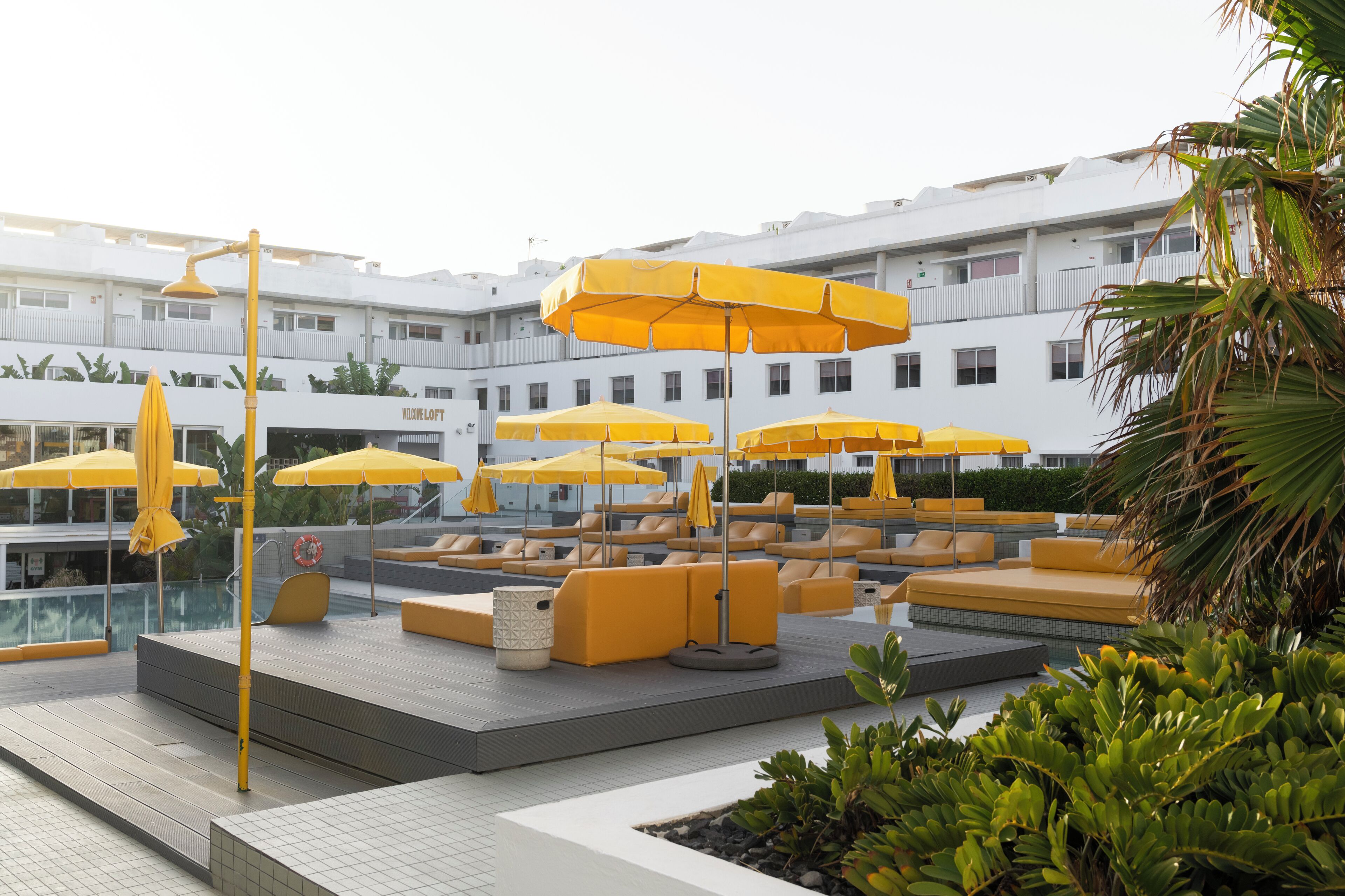 A rooftop pool area with yellow umbrellas and seating.