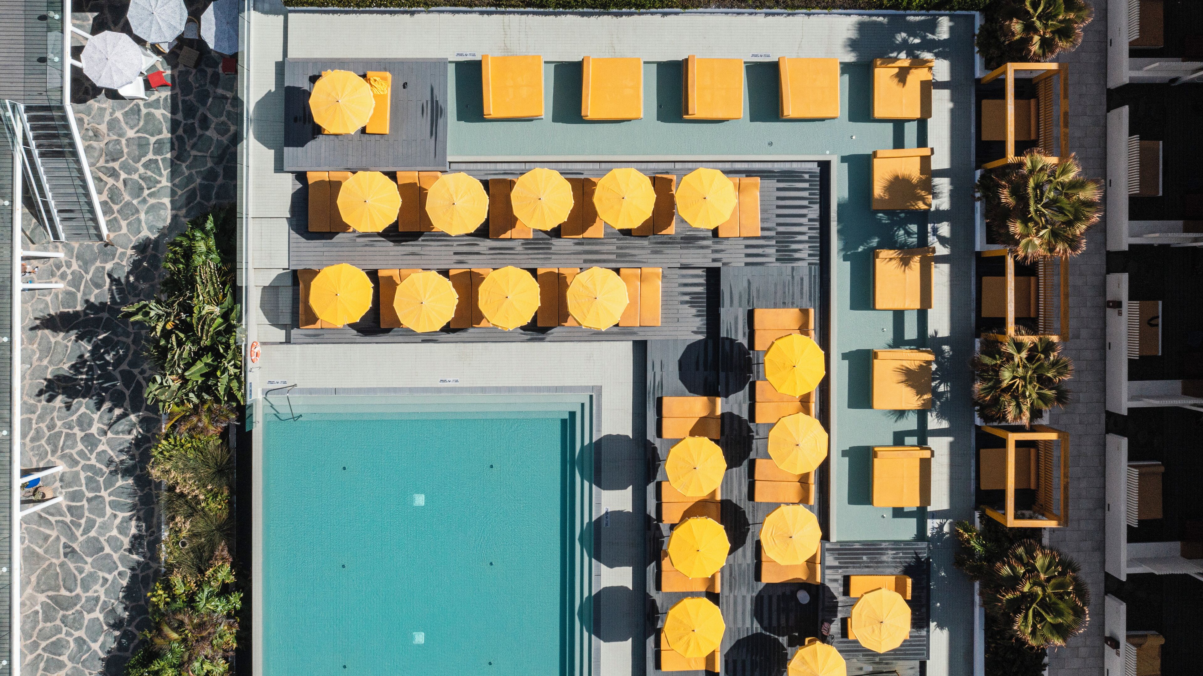 An aerial view of a poolside area with multiple seating arrangements and a central swimming pool.