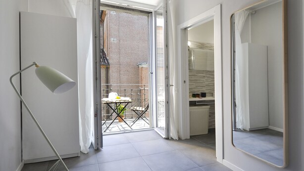 A modern interior with a sliding glass door leading to a balcony, a floor lamp, and a mirror. - At Home Heart of Milan - Bright City (Milan)