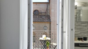 A balcony with a table set for dining, a potted plant, and a brick building in the background. - At Home Heart of Milan - Bright City (Milan)