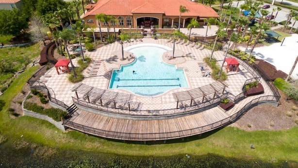 A resort with a central swimming pool, a covered deck, and a landscaped area with palm trees.
