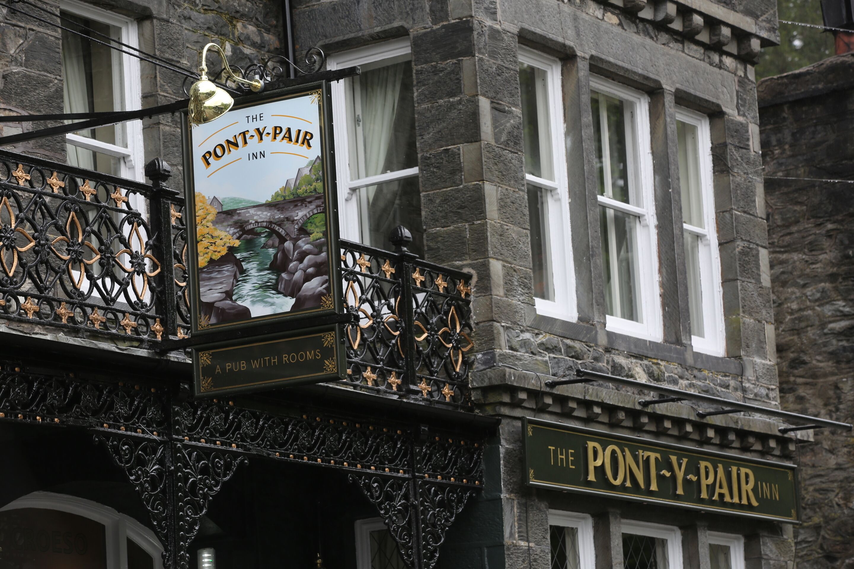 A pub with a balcony featuring ornate black ironwork and a sign that reads "The Pont-y-Pair Inn."