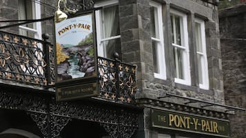 A pub with a balcony featuring ornate black ironwork and a sign that reads "The Pont-y-Pair Inn."