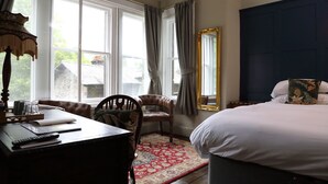 A bedroom with a large bed, a desk with a chair, a window with curtains, and a mirror. - Pont Y Pair Inn (Betws-Y-Coed)