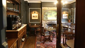 A cozy dining area with wooden furniture, a fireplace, and framed artwork on the walls. - Pont Y Pair Inn (Betws-Y-Coed)