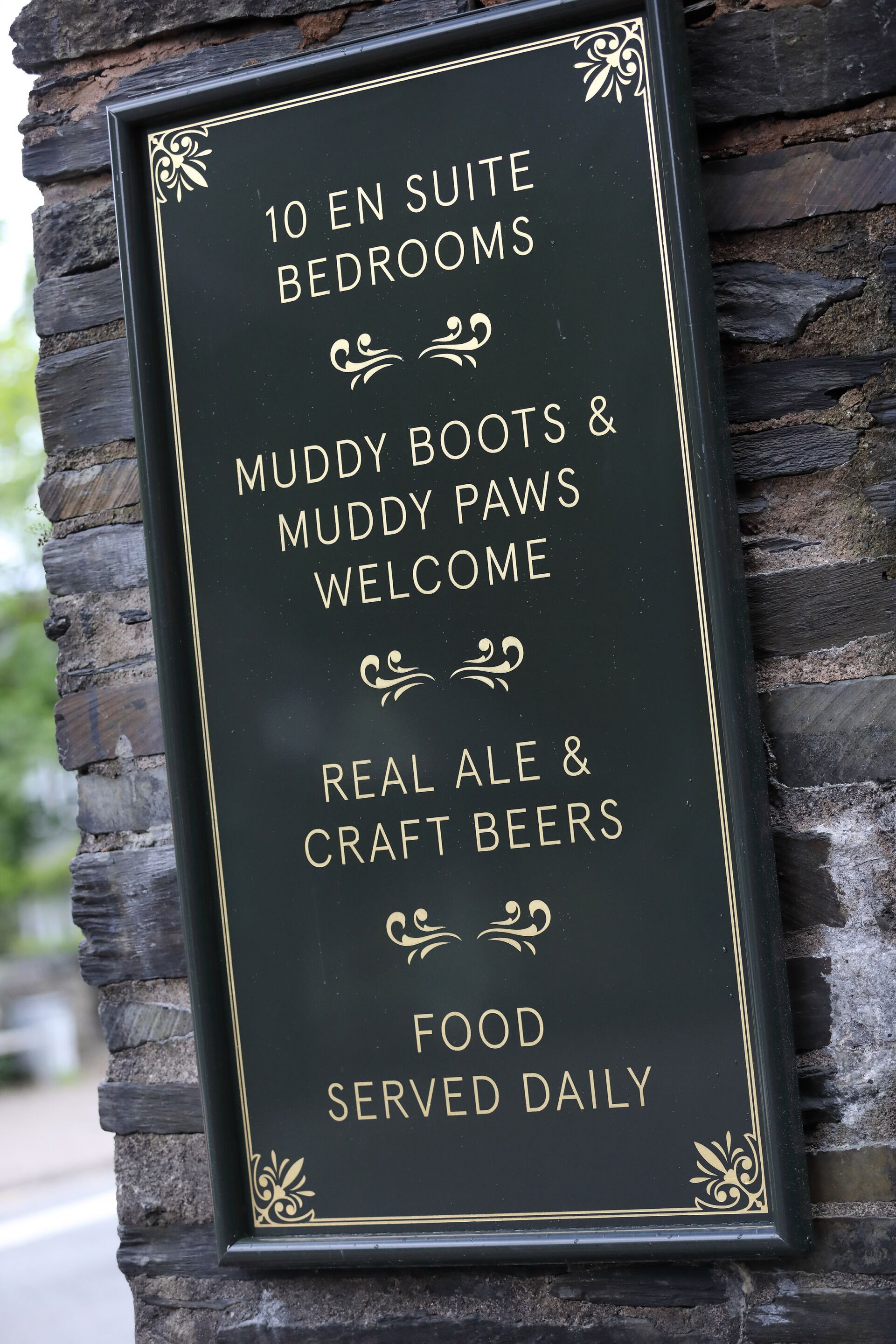 A sign advertising 10 en suite bedrooms, muddy boots & muddy paws welcome, real ale & craft beers, and food served daily.