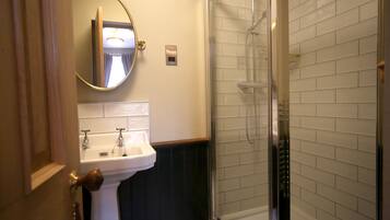 A bathroom with a sink, mirror, and shower.