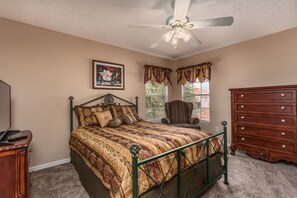 A bedroom with a bed, a dresser, a chair, a ceiling fan, and a window with curtains. - 6 Br Pool and Spa Home in Aviana Resort (Davenport)