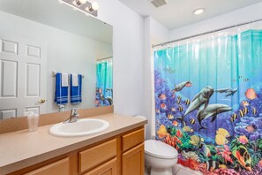 A bathroom with a white sink, a mirror, and a shower curtain depicting marine life. - 6 Br Pool and Spa Home in Aviana Resort (Davenport)