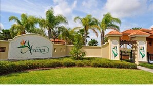 A sign with the name "Aviana" and a gated entrance with palm trees and a clear sky. - 4 Br Pool Home in Aviana Resort (Davenport)