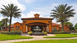 A large, orange building with a central fountain, surrounded by palm trees and well-maintained lawns. - 4 Br Pool Home in Aviana Resort (Davenport)