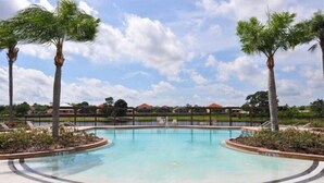A swimming pool with a clear blue water, surrounded by palm trees and a fence. - 4 Br Pool Home in Aviana Resort (Davenport)