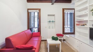 Ein modernes Wohnzimmer mit einem roten Sofa, einem weißen Couchtisch und einem Fernseher auf einem weißen Schrank.