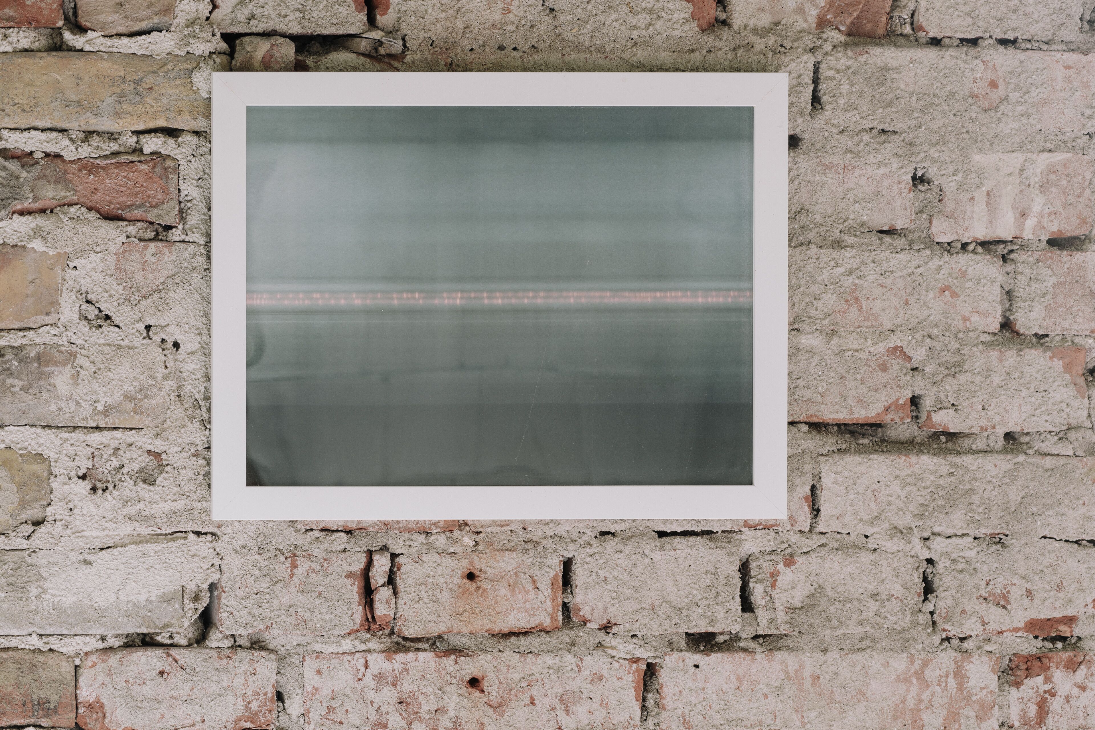 A framed picture on a brick wall.