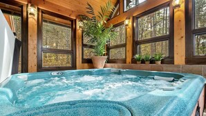 Ein Whirlpool mit Blick auf einen Wald durch große Fenster.