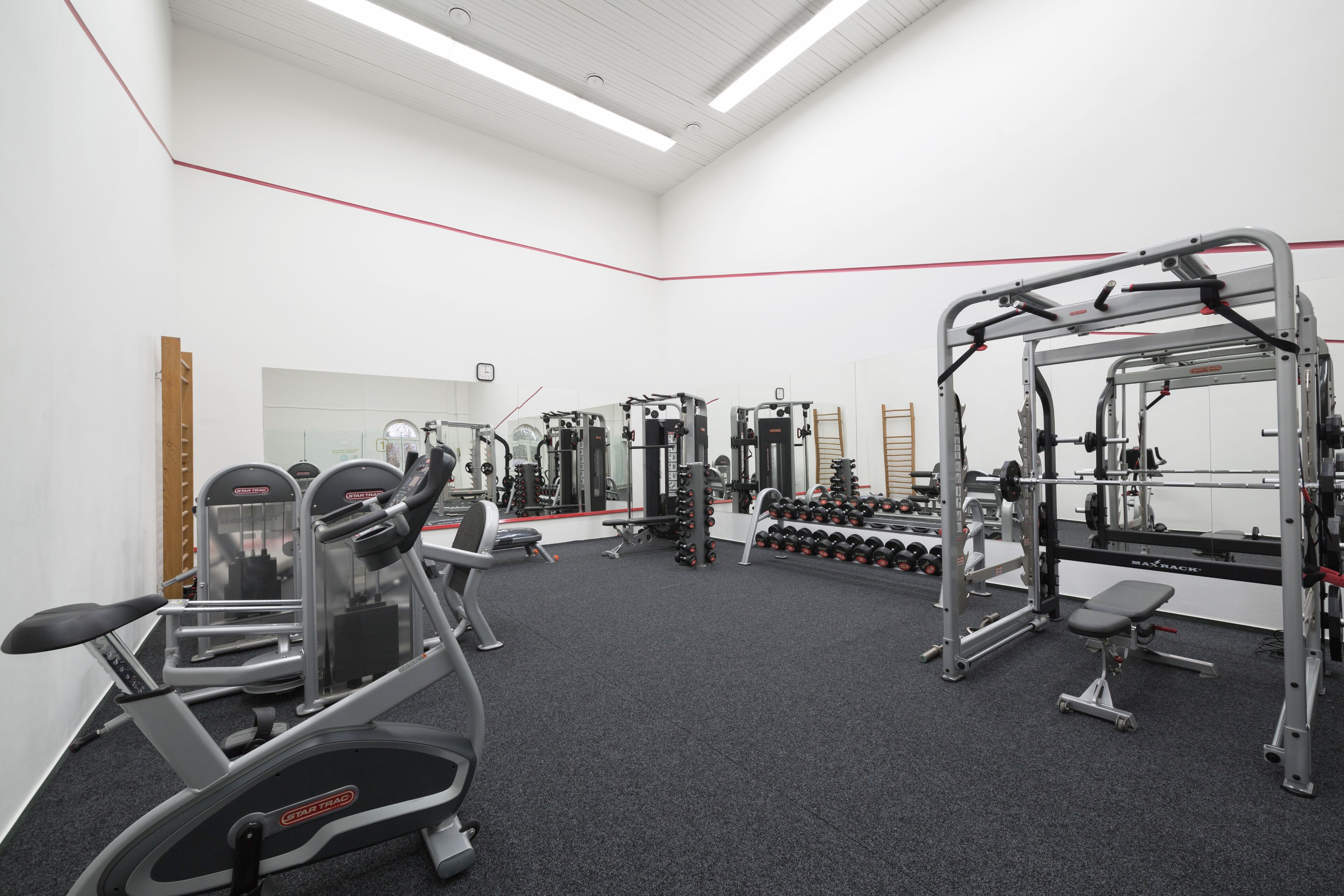 Une salle de sport équipée de machines de cardio, d’appareils de musculation et d’haltères.