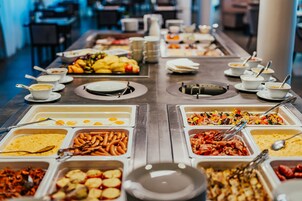 Un bufé con diversas opciones de comida, como huevos, salchichas y ensaladas.