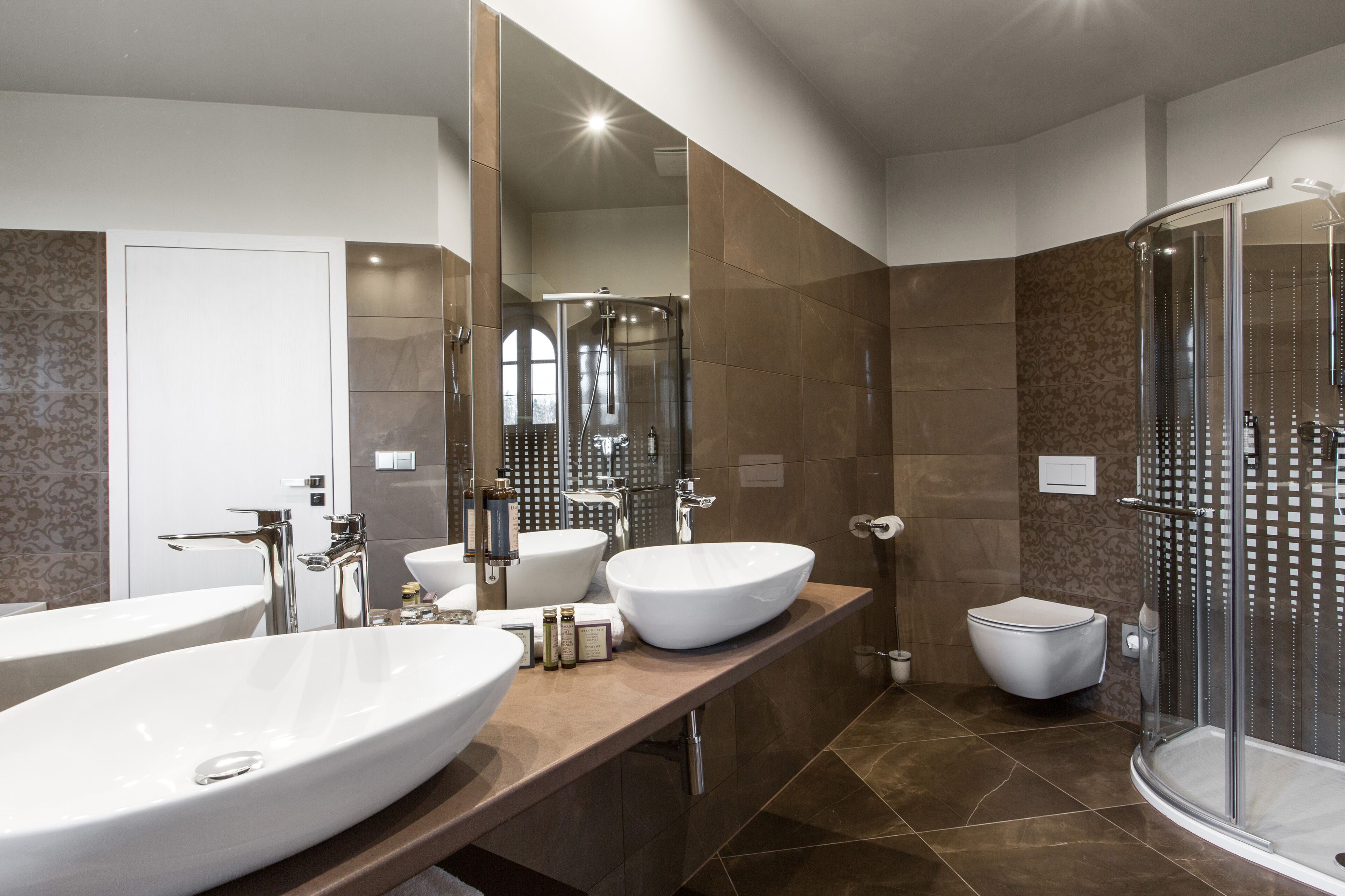 Un baño moderno con dos lavamanos grandes, una ducha y un inodoro.