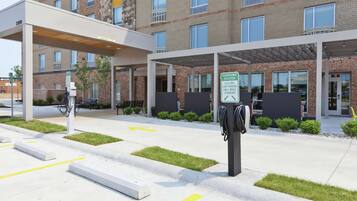 A modern building with a covered parking area, electric car charging station, and a sign indicating a charging station.