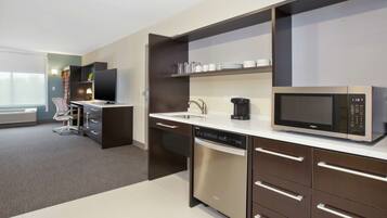 A modern kitchen with a dishwasher, microwave, and a coffee maker on the counter.