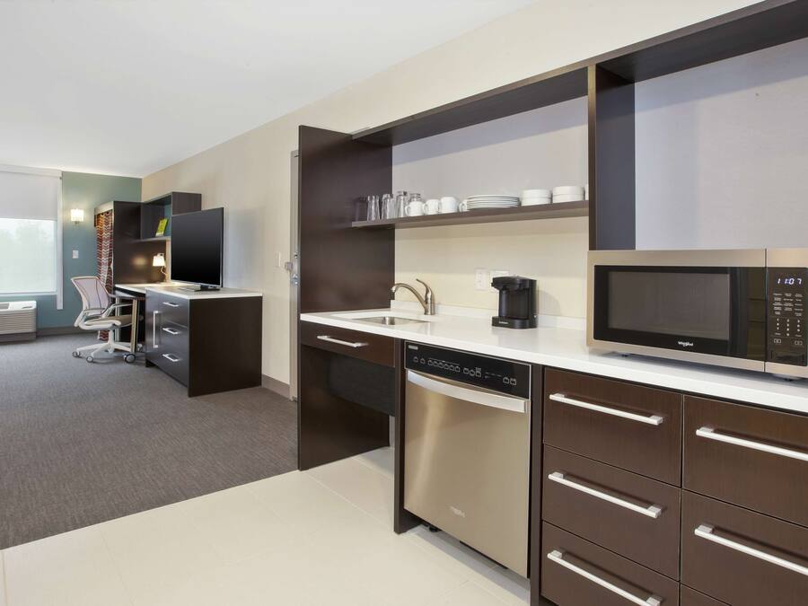 A modern kitchen with a dishwasher, microwave, and a coffee maker on the counter.