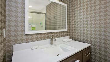 A bathroom with a white sink, a mirror, and a towel rack.