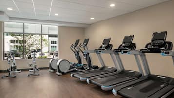 Un gimnasio con cintas de correr, elípticas y una máquina de remo.