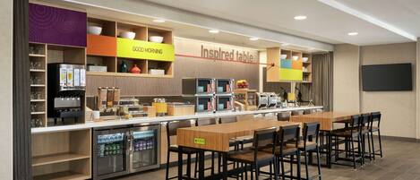A modern kitchen area with a long counter, multiple appliances, and a dining table with chairs.