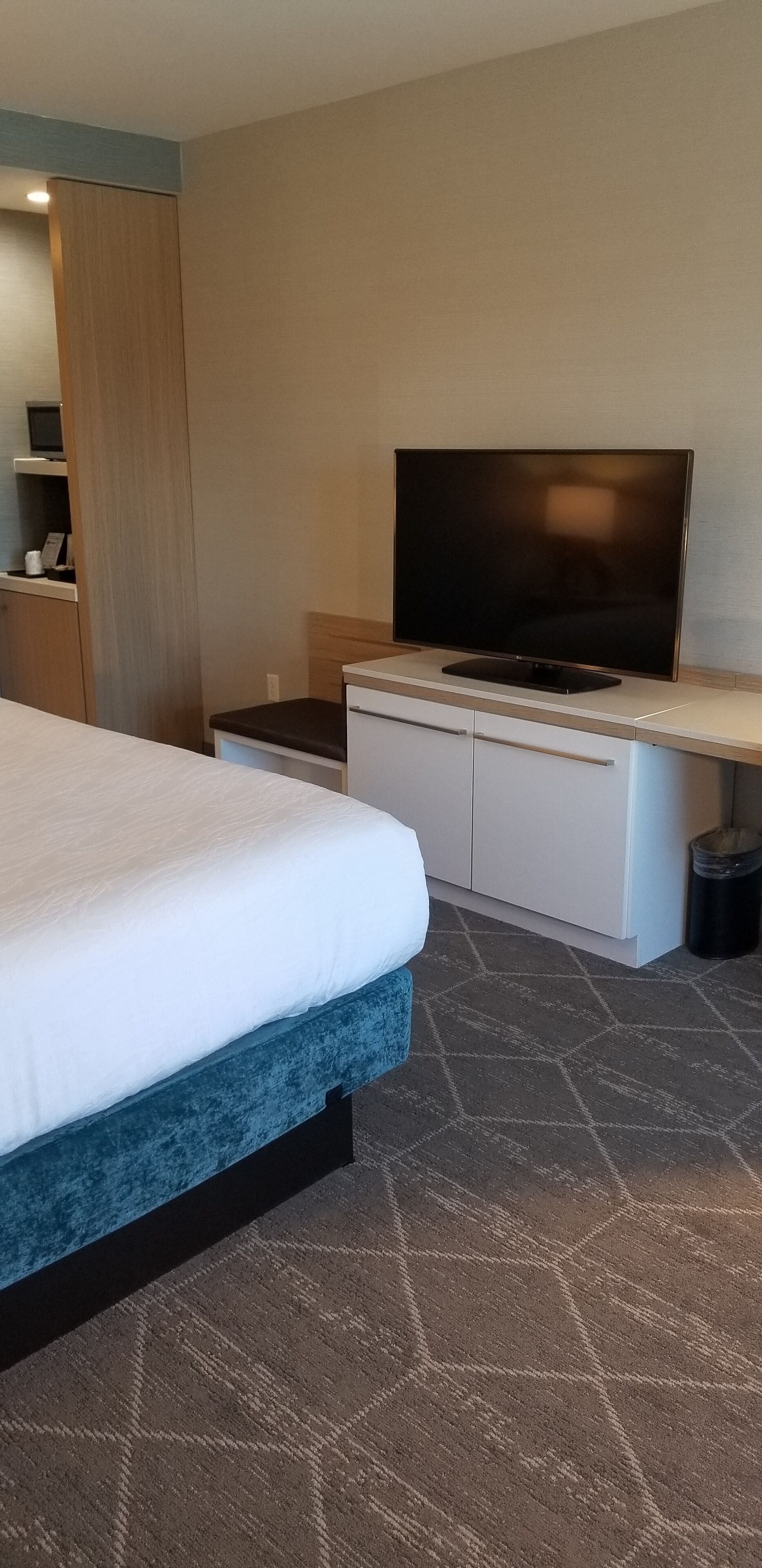 Ein Hotelzimmer mit Bett, Fernseher, Schreibtisch und Kleiderschrank.