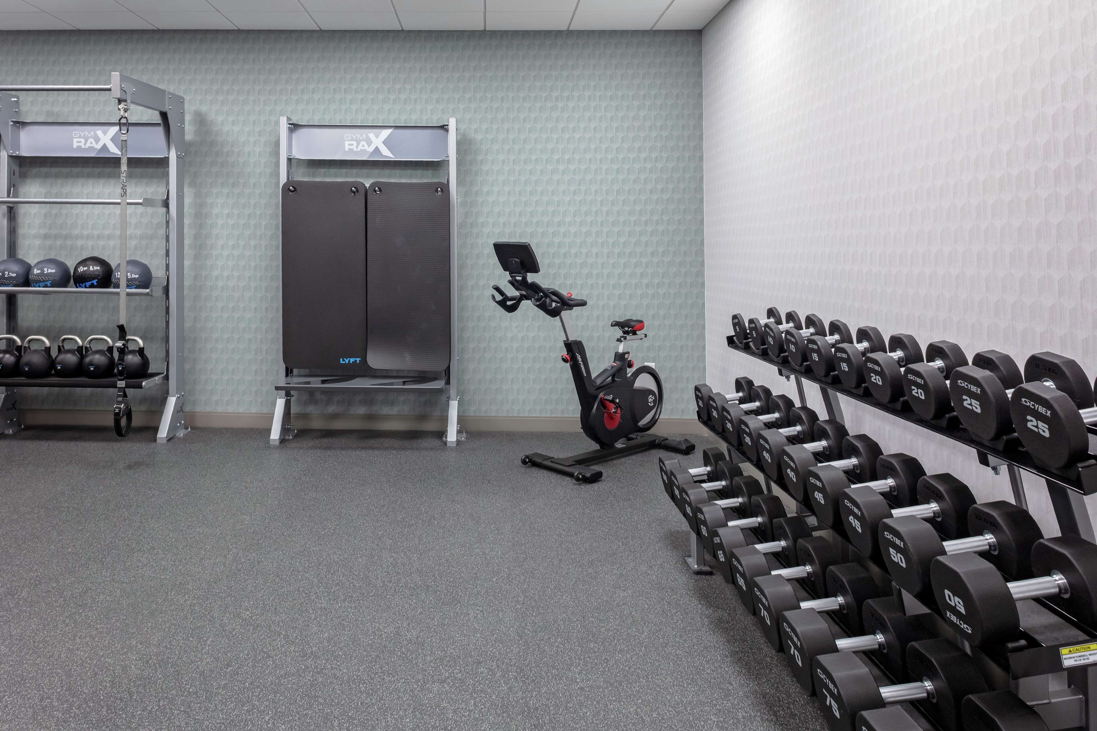 A gym with weightlifting equipment, exercise bikes, and a wall-mounted rack.
