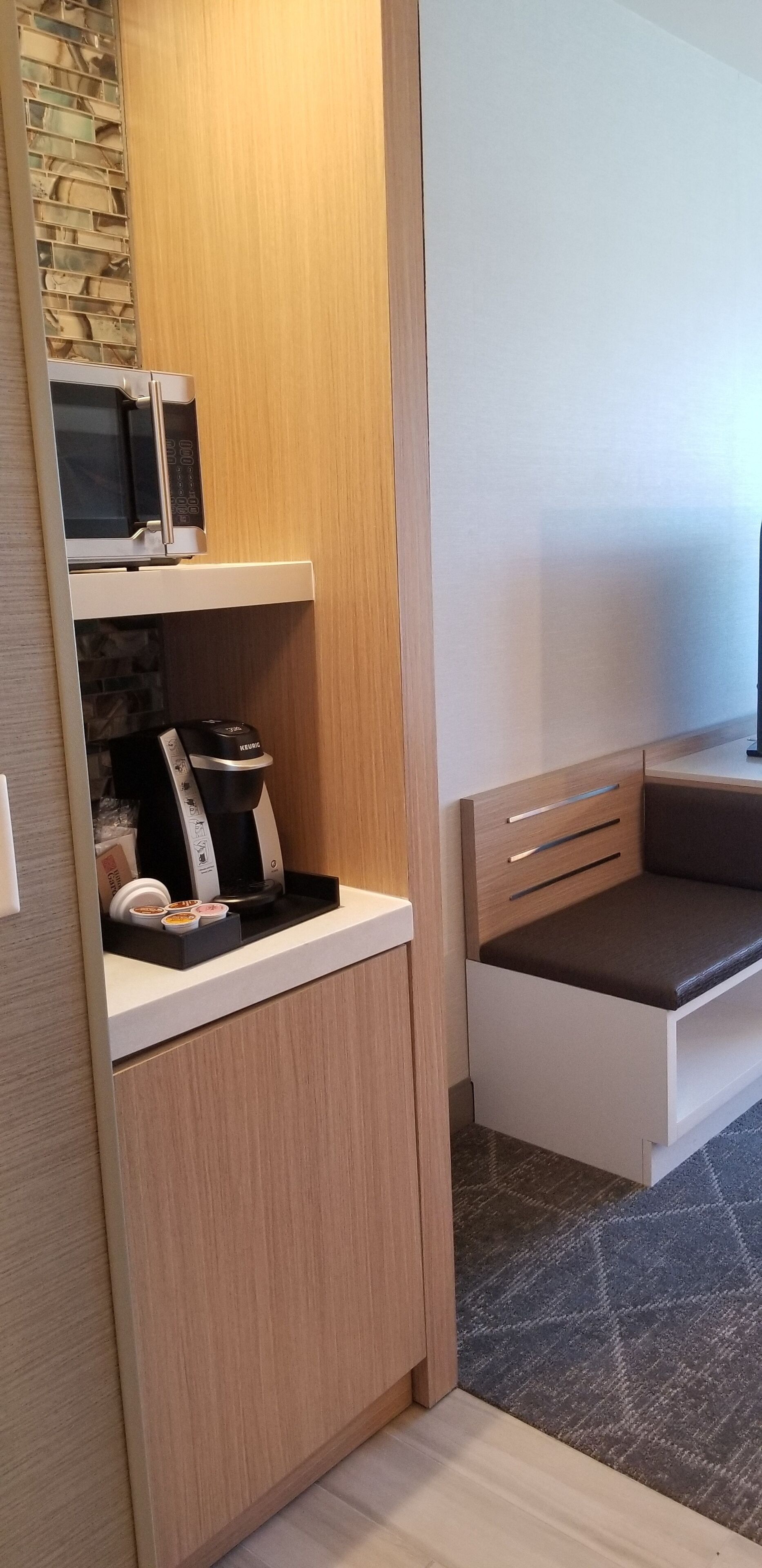 A compact kitchenette with a microwave, coffee maker, and tea set.