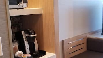 A compact kitchenette with a microwave, coffee maker, and tea set.