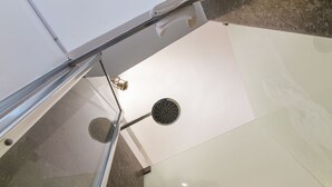Un coin de pièce avec un sol carrelé de carreaux blancs, un élément en métal et un mur blanc.