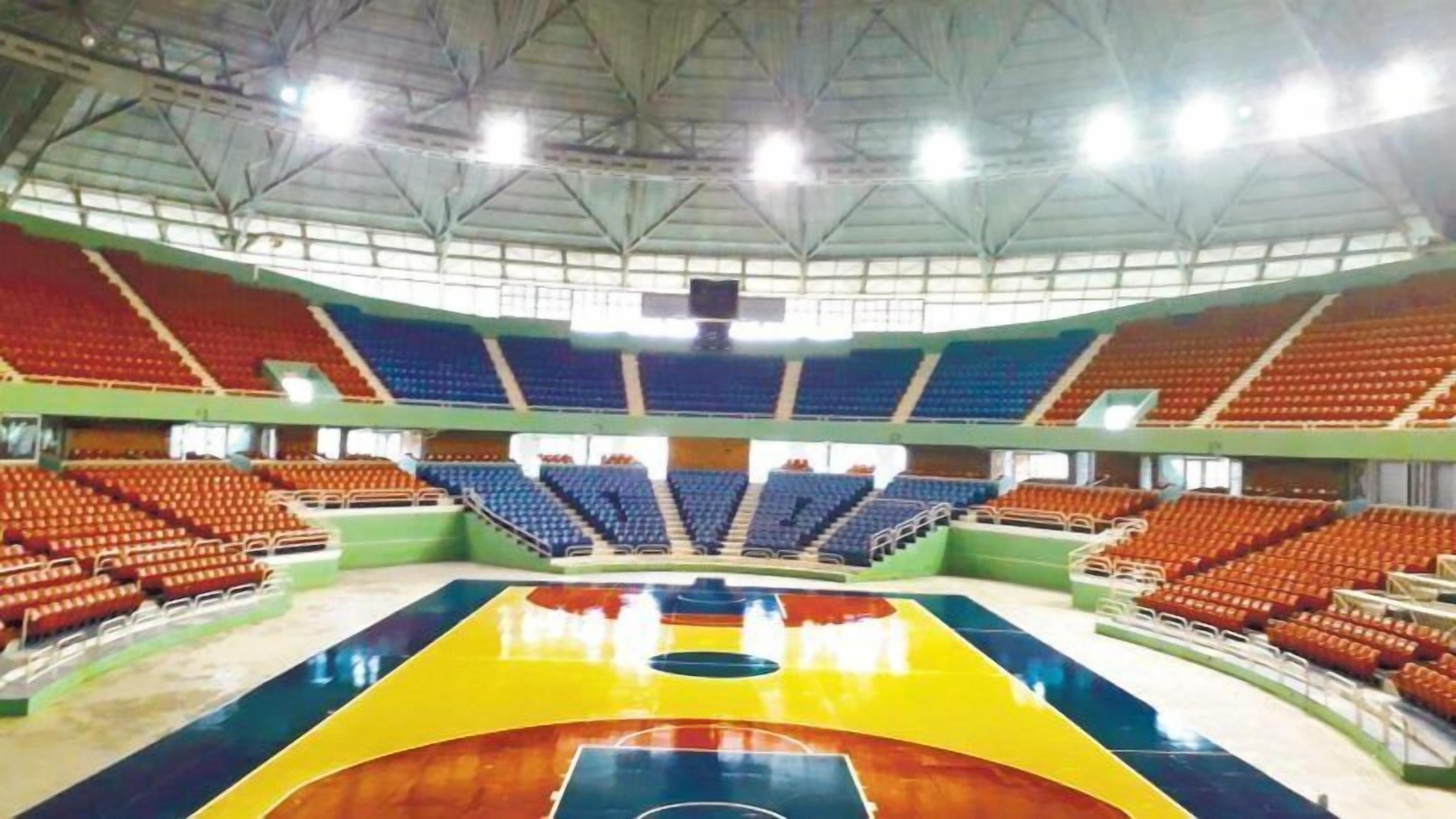 An indoor basketball court with multiple seating sections and a high ceiling.