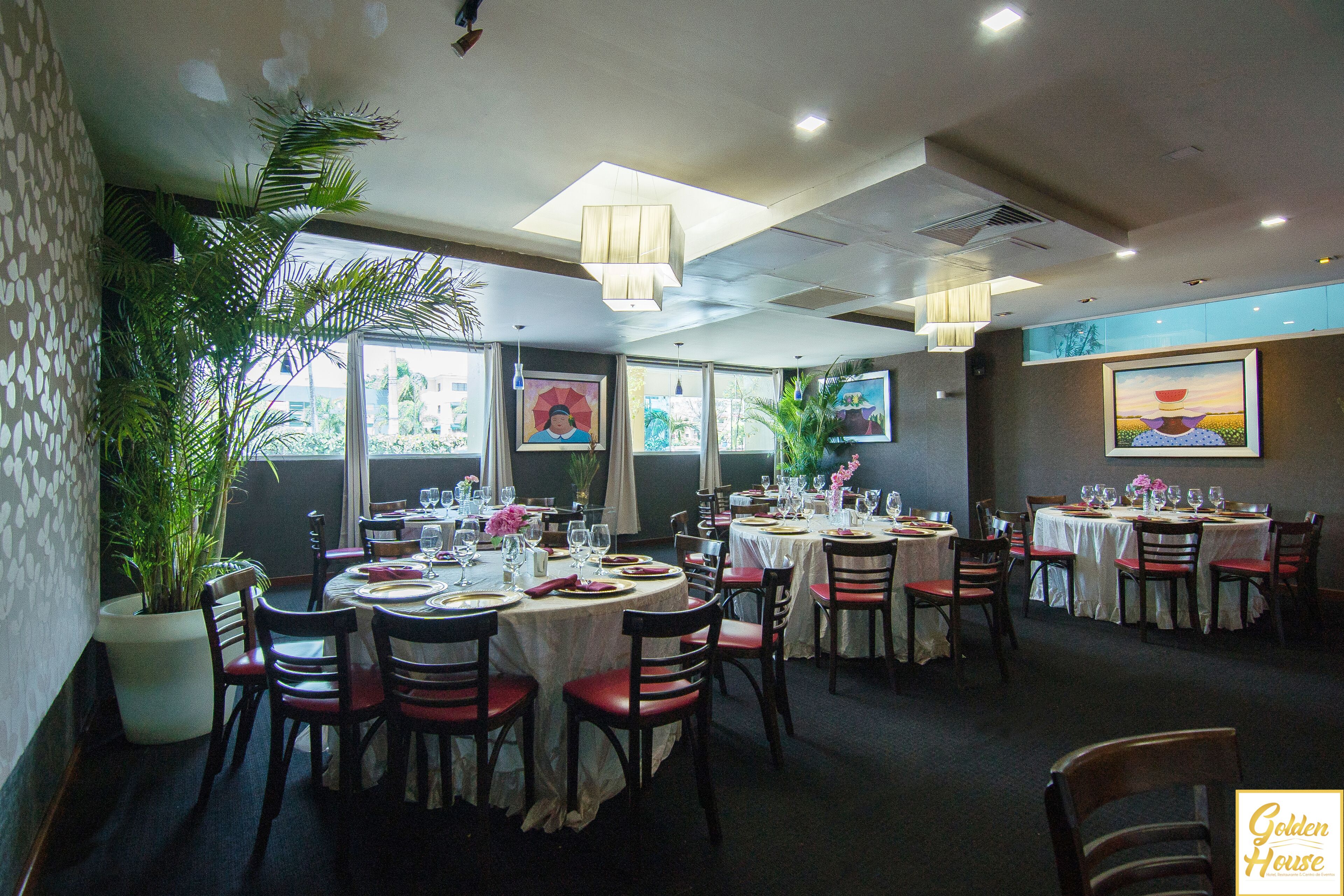 Een restaurant met meerdere ronde tafels, stoelen en potplanten.