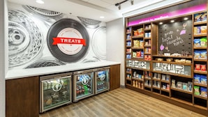 A snack and sundries section with a 'Treats' sign, refrigerated display cases, and shelves stocked with various snacks. - Hampton Inn Madison (Madison)