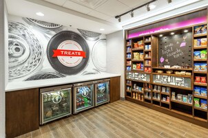 Una sección de aperitivos y artículos varios con un letrero que dice 'Treats', vitrinas refrigeradas y estantes llenos de diferentes bocadillos.