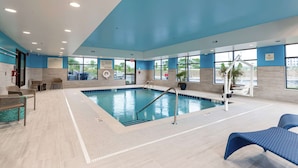 An indoor swimming pool with clear water, surrounded by lounge chairs and a lifeguard sign. - Hampton Inn Madison (Madison)