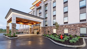 A Hampton Inn hotel entrance with a covered walkway, stone facade, and a fire hydrant in the landscaping. - Hampton Inn Madison (Madison)