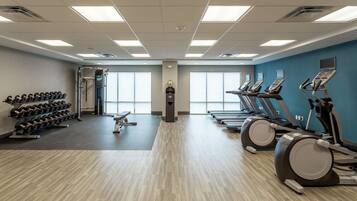 A gym with treadmills, elliptical machines, and a rack of dumbbells.