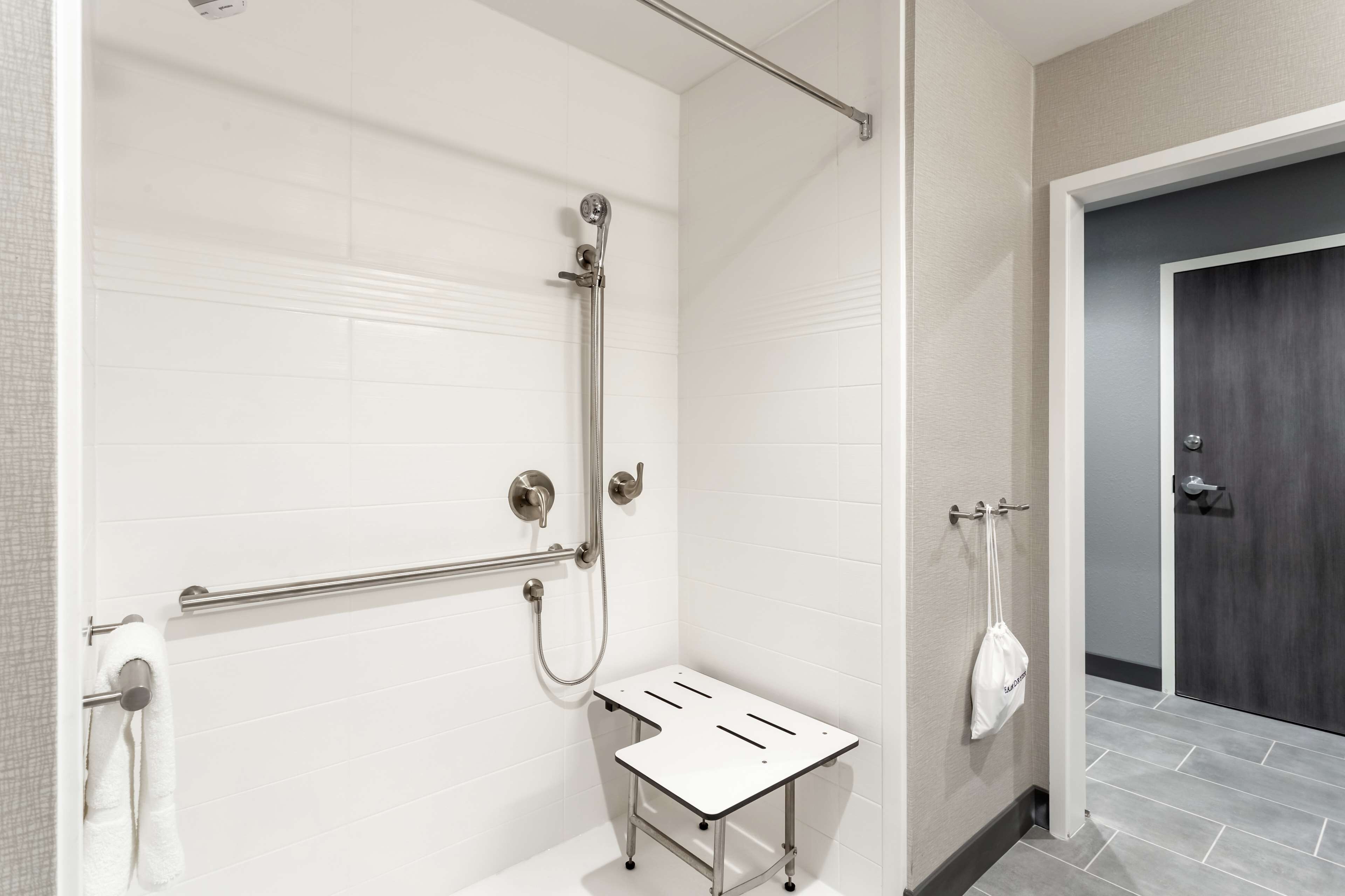 A modern bathroom with a shower, a towel rack, and a small table.