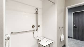 A modern bathroom with a shower, a towel rack, and a small table.