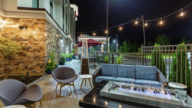 An outdoor patio with a fire pit, seating, and string lights. - Hampton Inn Madison (Madison)