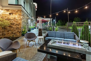 Un patio al aire libre con un pozo de fuego, asientos e iluminación colgante.